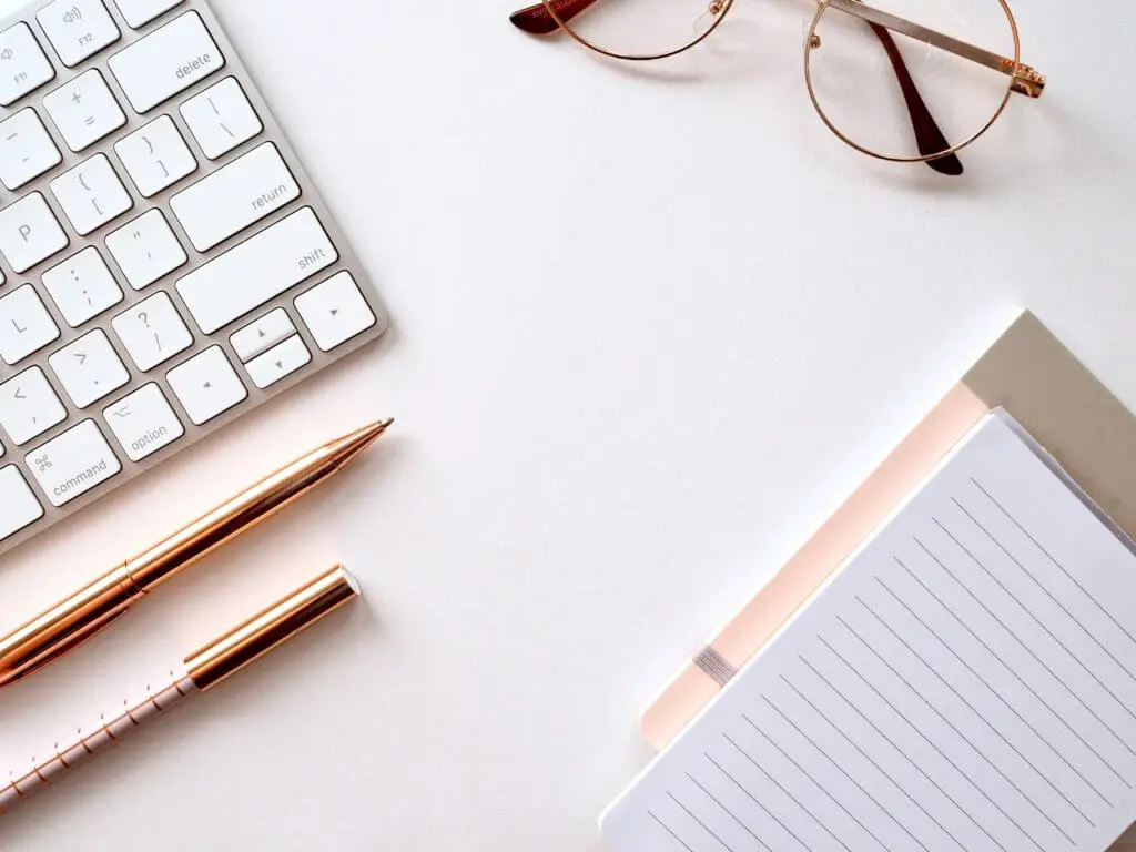 A notepad, glasses, and keyboard sitting on a white table—Stratice blog cover