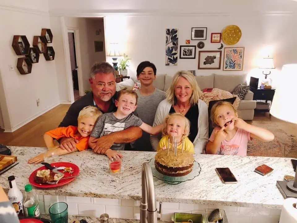 The Hampton family and all their grandkids posing around a birthday cake.