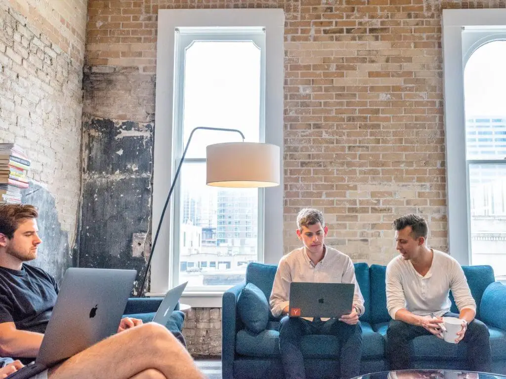 Four men sitting on couches in an office, working on laptops—Stratice blog cover