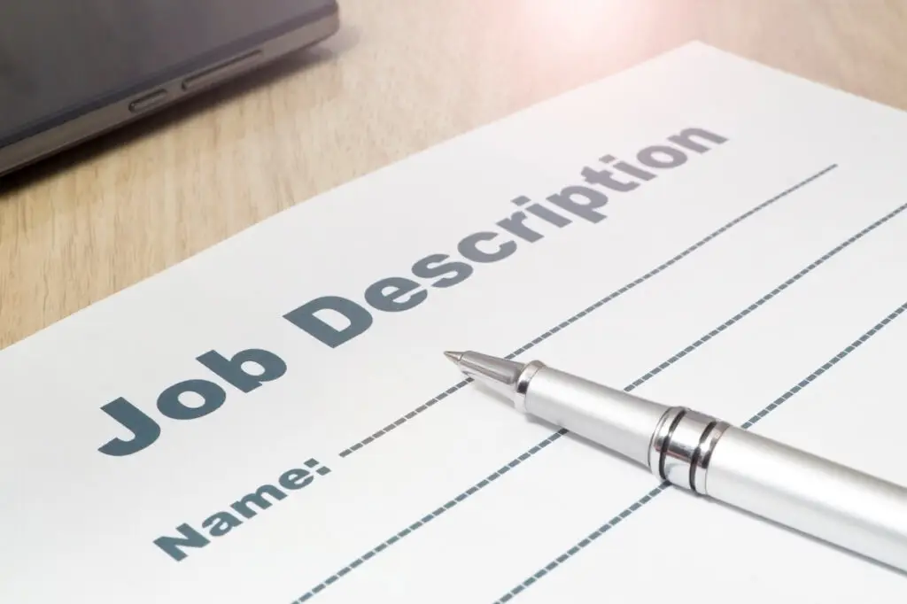 A paper on the table titled Job Description with a space for the name underneath and a pen resting on top.